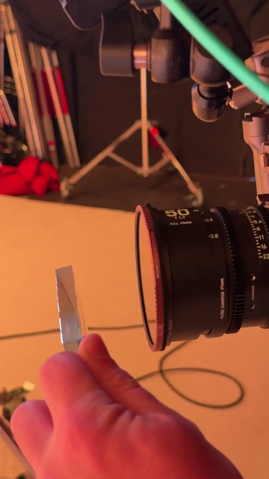A hand holding a filter up to a 50mm prime on set