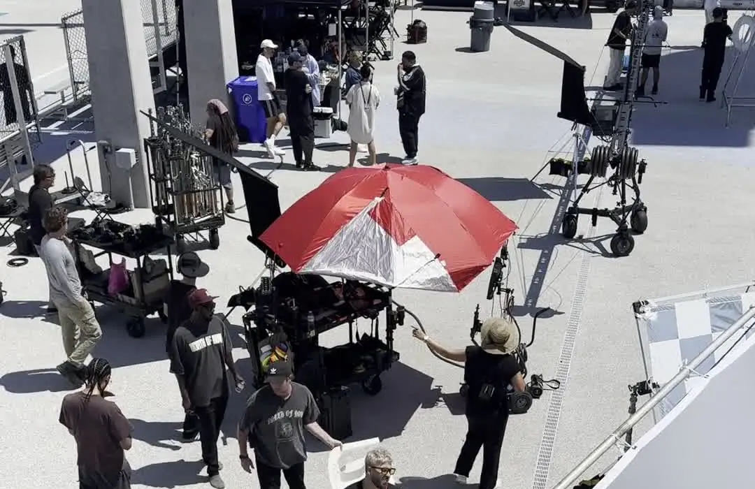 A MUUS unit at work on a rooftop set. Grip carts, a lighting umbrella, a large silk frame and crew moving between them